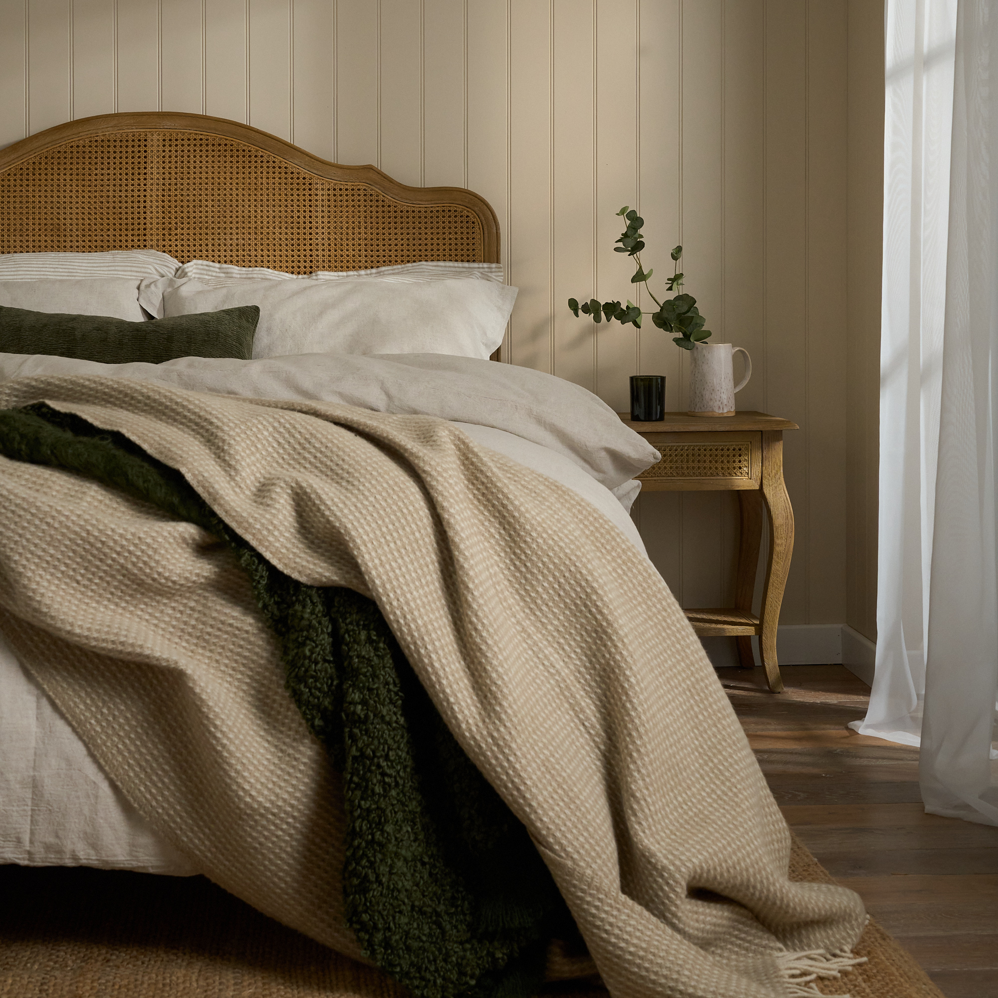 Cane headboard bed with natural linen and waffle throw