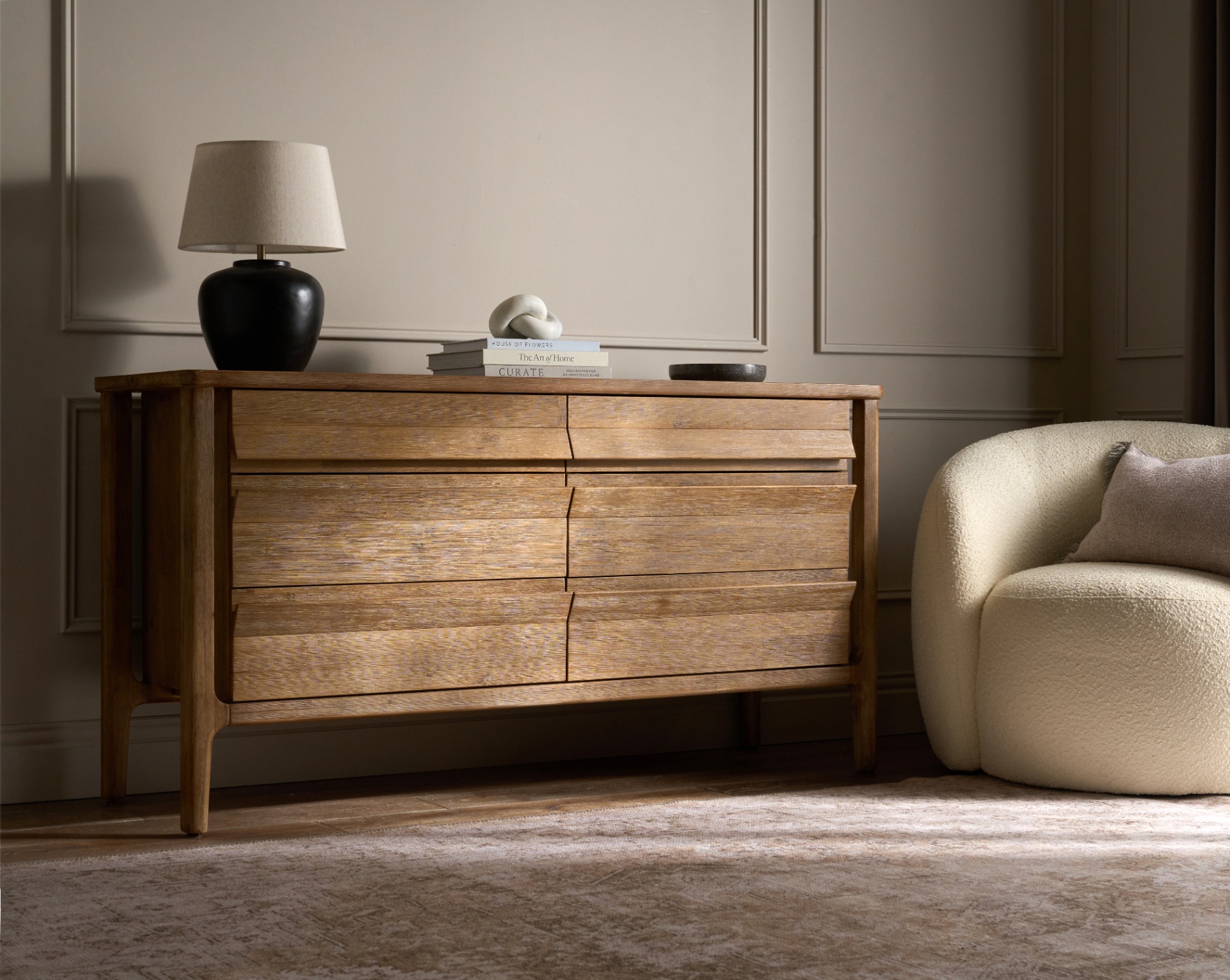 Limed oak dresser with black lamp and boucle chair