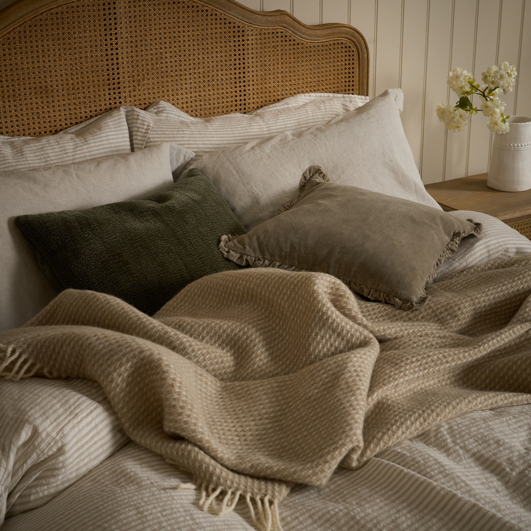 Layered cushions, linen and waffle throw on cane bed
