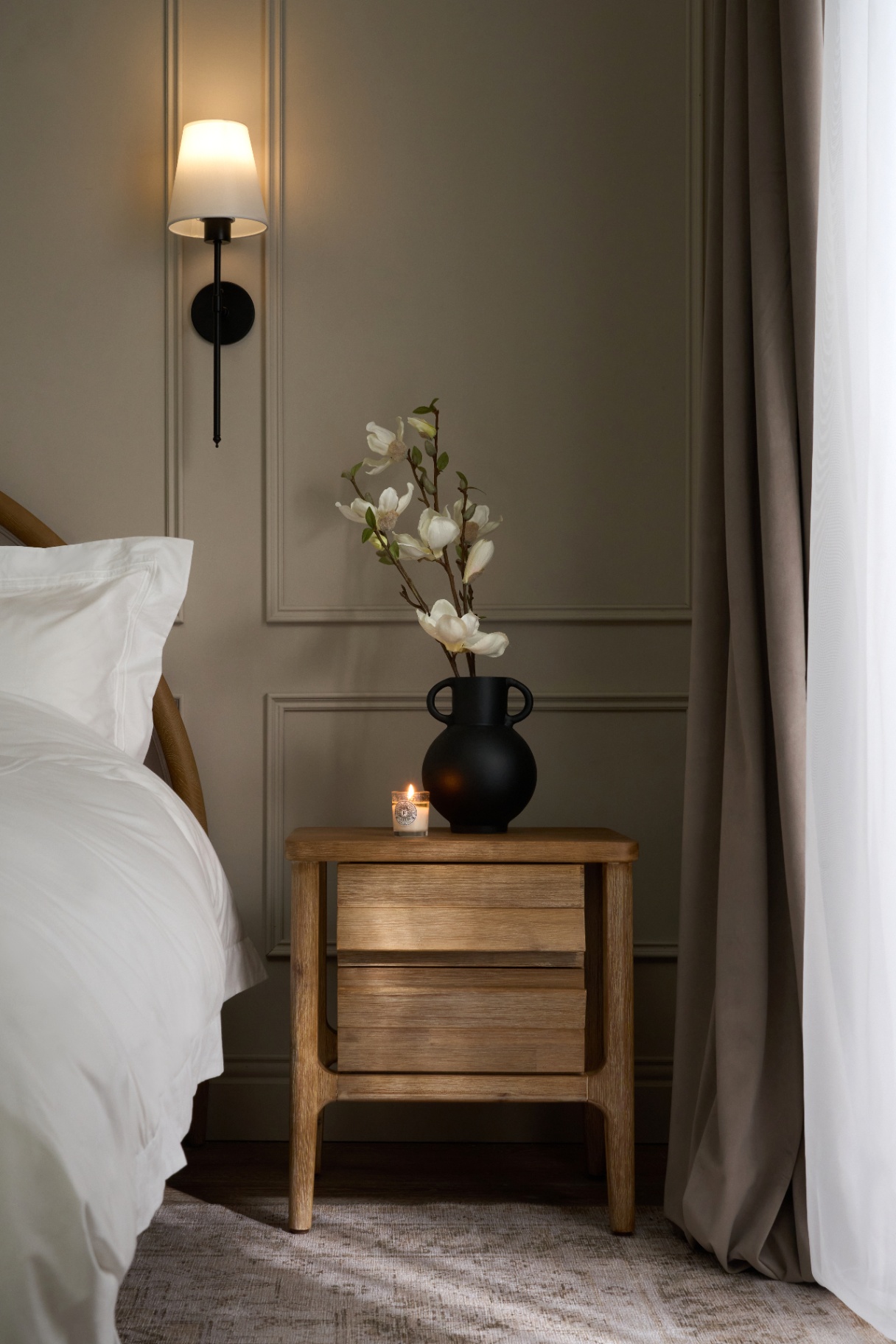Oak nightstand with black vase and magnolia stems